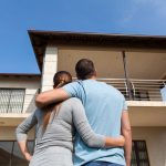 Rear,View,Of,Young,Couple,Looking,At,Their,New,House